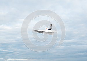 Businessman in aviator hat sitting in paper plane