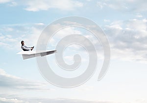 Businessman in aviator hat sitting in paper plane