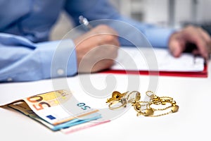 Businessman in the back, euro banknotes and gold jewellry in the front photo