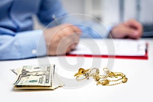 Businessman in the back, us dollars and gold jewellry in the front photo