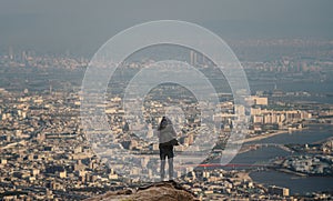 Businessman with backpack standing on summit looking city view with air pollution environment