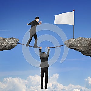 Businessman balancing on broken chain another man holding toward