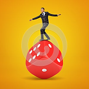Businessman balancing on a giant red dice