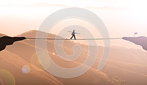 Businessman Balancing On Rope Between two Maintains Cliff At Sunset.