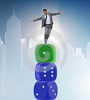 Businessman balancing on top of dice stack in uncertainty concep