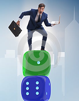 Businessman balancing on top of dice stack in uncertainty concep