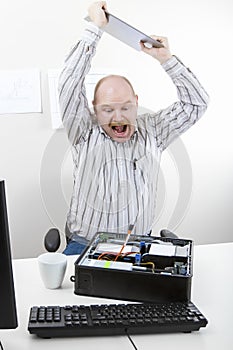 Businessman Banging File On Computer Chassis At Table photo