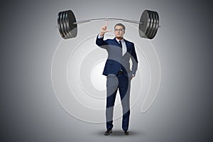 The businessman with barbell in heavy lifting concept