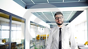businessman with beard and glasses, in business clothes, walks along the corridor of a modern office