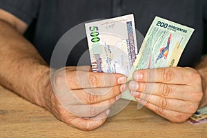 Businessman behind the desk holds 200 and 500 Honduran Lempiras banknotes in his hand, Honduras money, Banking investment