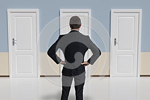 Businessman from behind is making decision and selecting the door