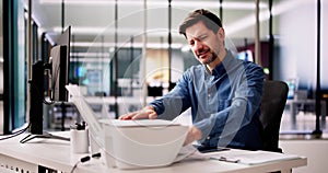 Businessman Bend Down To Remove Paper Stuck In Printer