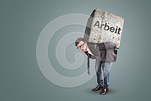 Businessman bending under a heavy stone with the German word `Arbeit` written on it