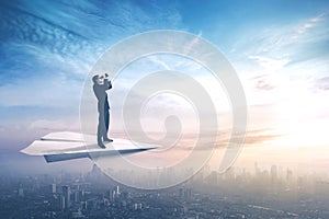 Businessman with binoculars on paper aircraft