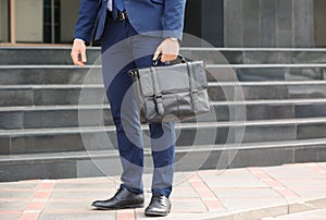 Businessman with black briefcase in hand outdoors.