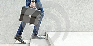 Businessman with black briefcase in hand walking up on stairs