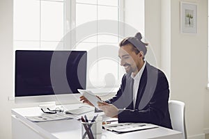 A businessman in a black jacket works analyzes strategy at the computer in the office.