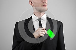 Businessman in a black suit and black tie holding a card, a hand holding a card, green card, card is inserted, the green chroma