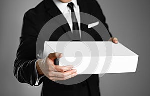 Businessman in a black suit holding a white box. Close up. Isolated background