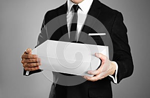 Businessman in a black suit holding a white box. Close up. Isolated background