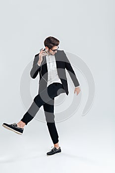 Businessman in black suit listening music with earphones and dancing