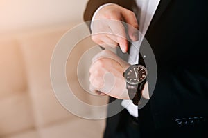 Businessman in black suit look at his expensive swiss wristwatch on his hand and watching the time