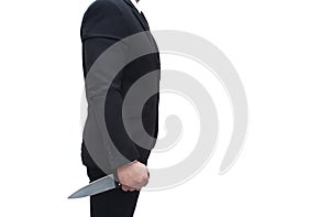 A businessman in a black suit stands holding a knife