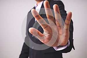 A businessman in a black suit stands and raises his hands