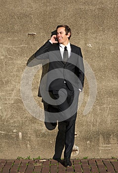 Businessman in black suit talking on mobile phone outdoors