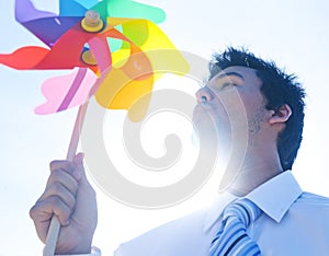 Businessman blowing pinwheel relaxation concept