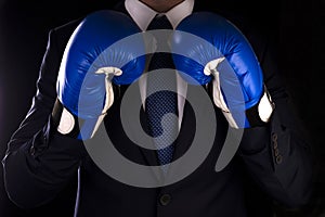 Businessman in blue boxing gloves on a dark background