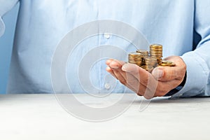 Businessman in a blue shirt holds in his hand lot of coins. Copy space for text.