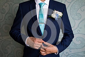 Businessman in blue suit tying the necktie. Smart casual outfit. Man getting ready for work.The morning of the groom