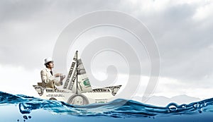 Businessman in boat made of dollar banknote