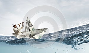 Businessman in boat made of dollar banknote