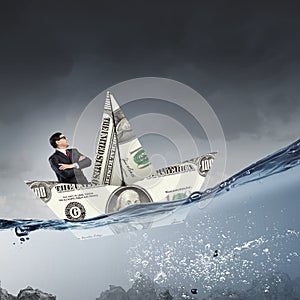 Businessman in boat made of dollar banknote