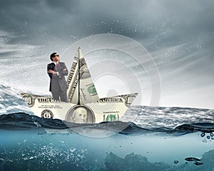 Businessman in boat made of dollar banknote
