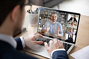 View over businessman shoulder laptop screen and videocall diverse participants photo