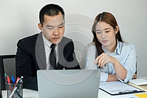 Businessman boss in suit explaining about new business project to her and woman office worker is pointing