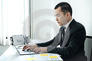 Businessman boss in suit to analysis of investments in new business from chart and document during to typing new idea