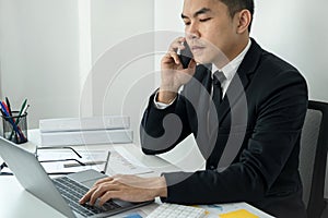 Businessman boss using smartphone talking with client about new business investment and typing on laptop
