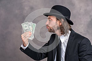 Businessman with bowler hat in black suit showing money