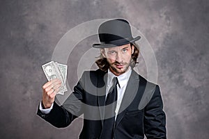 Businessman with bowler hat in black suit showing money