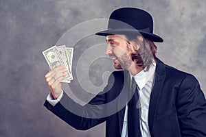 Businessman with bowler hat in black suit showing money