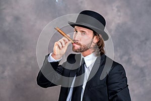 Businessman with bowler hat in black suit smoking big cigar