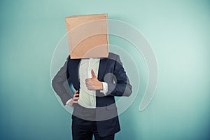 Businessman with box on his head giving thumb up