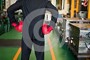 Businessman with boxing gloves in factory