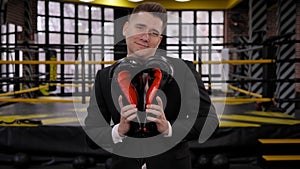 A businessman with boxing gloves, he holds gloves in the shape of a heart.