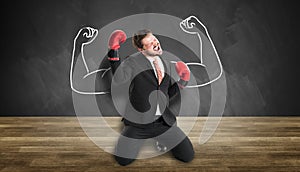 Businessman with boxing gloves and powerful pose cheering in front of a chalkboard