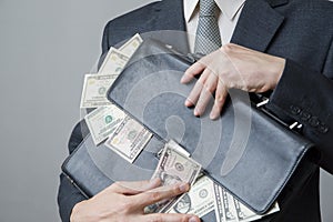 Businessman with a briefcase full of money in the hands of